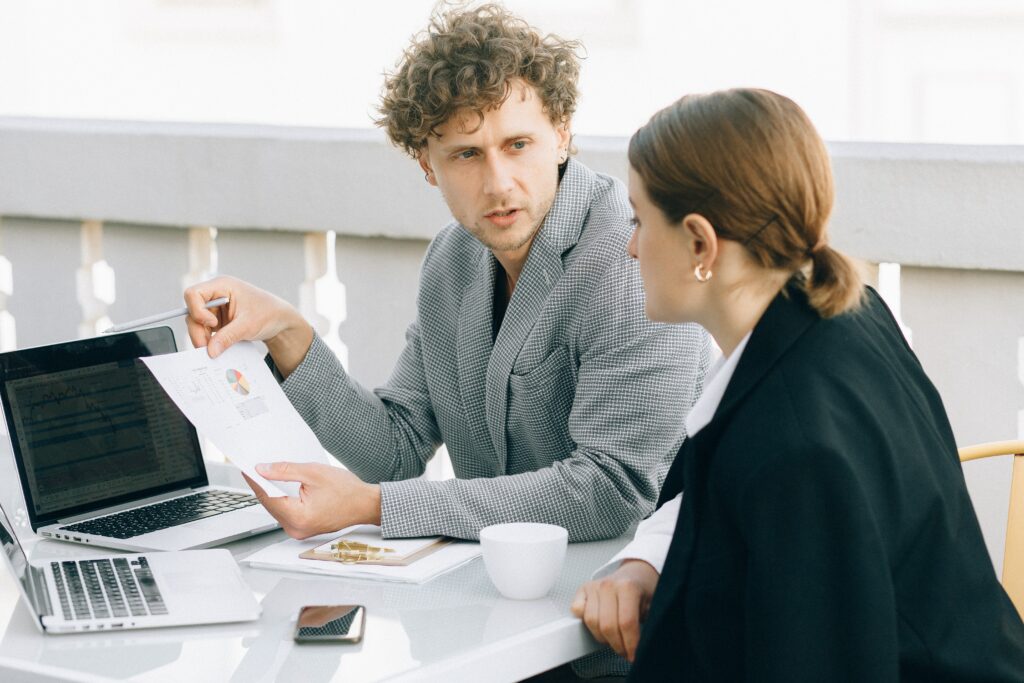 A man and woman look at a laptop in a white office.