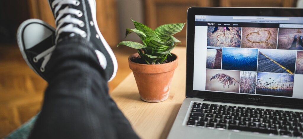 A laptop sits on a coffee table. The user has propped up their feet on the table beside the laptop.