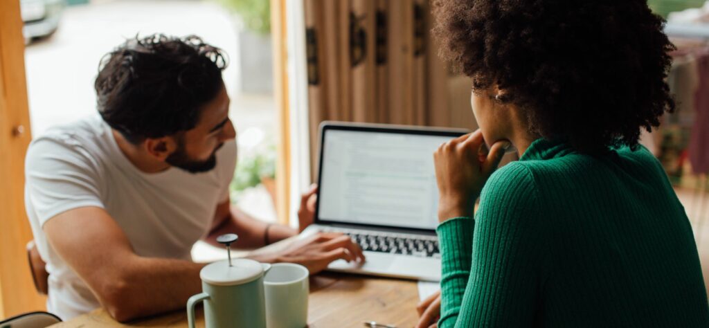 A man and woman work on a laptop together.