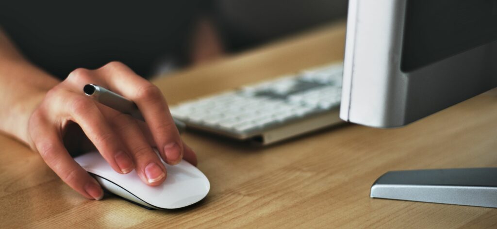 A photograph of a woman's hand on a computer mouse.